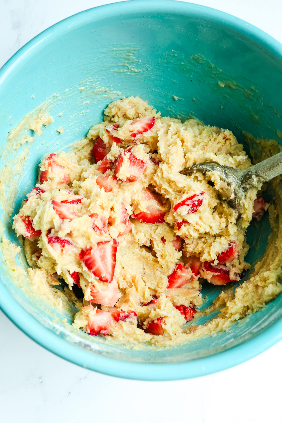a thick pie dough with strawberries in a turquoise bowl