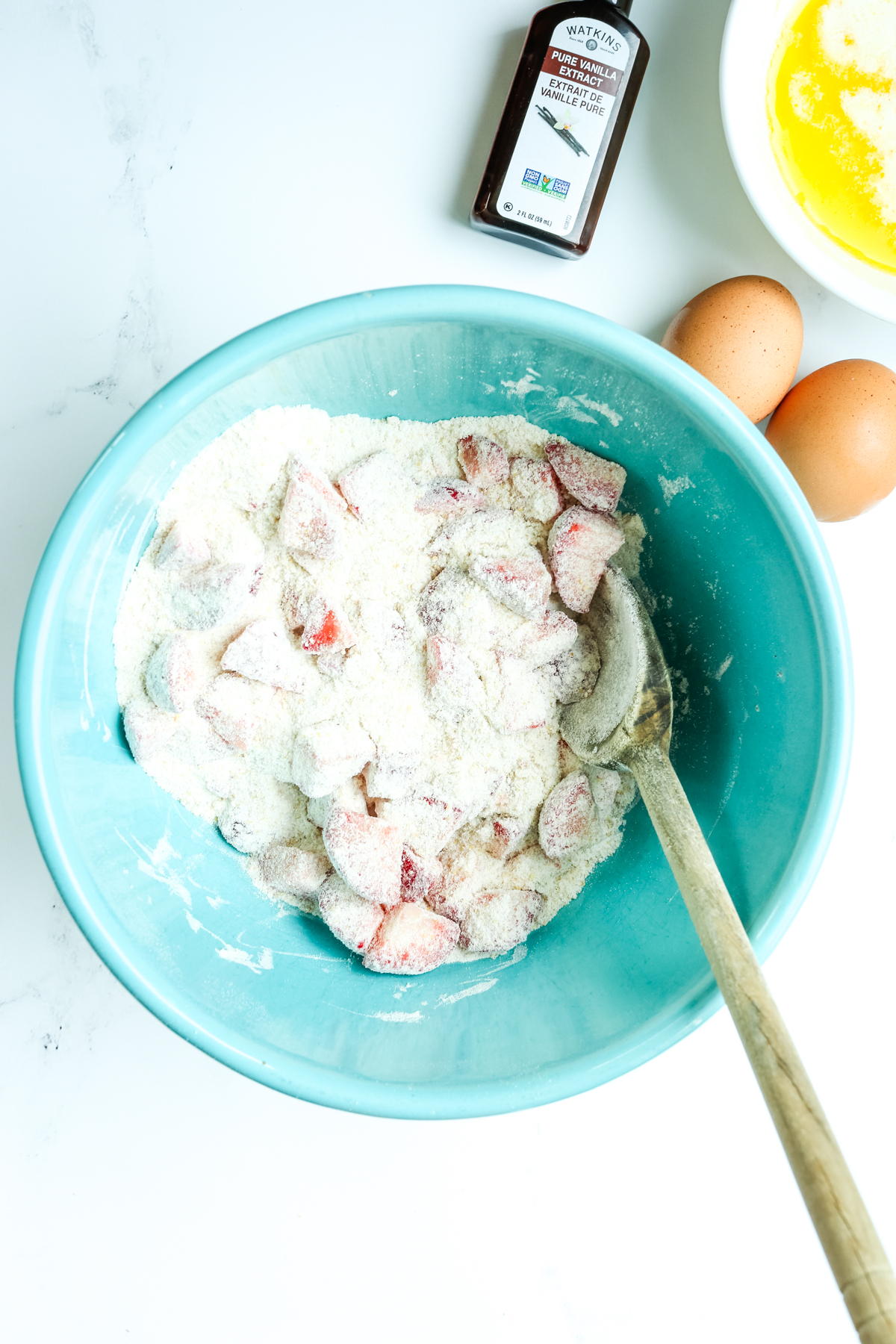 strawberries and flour mixed together in a turquoise bowl