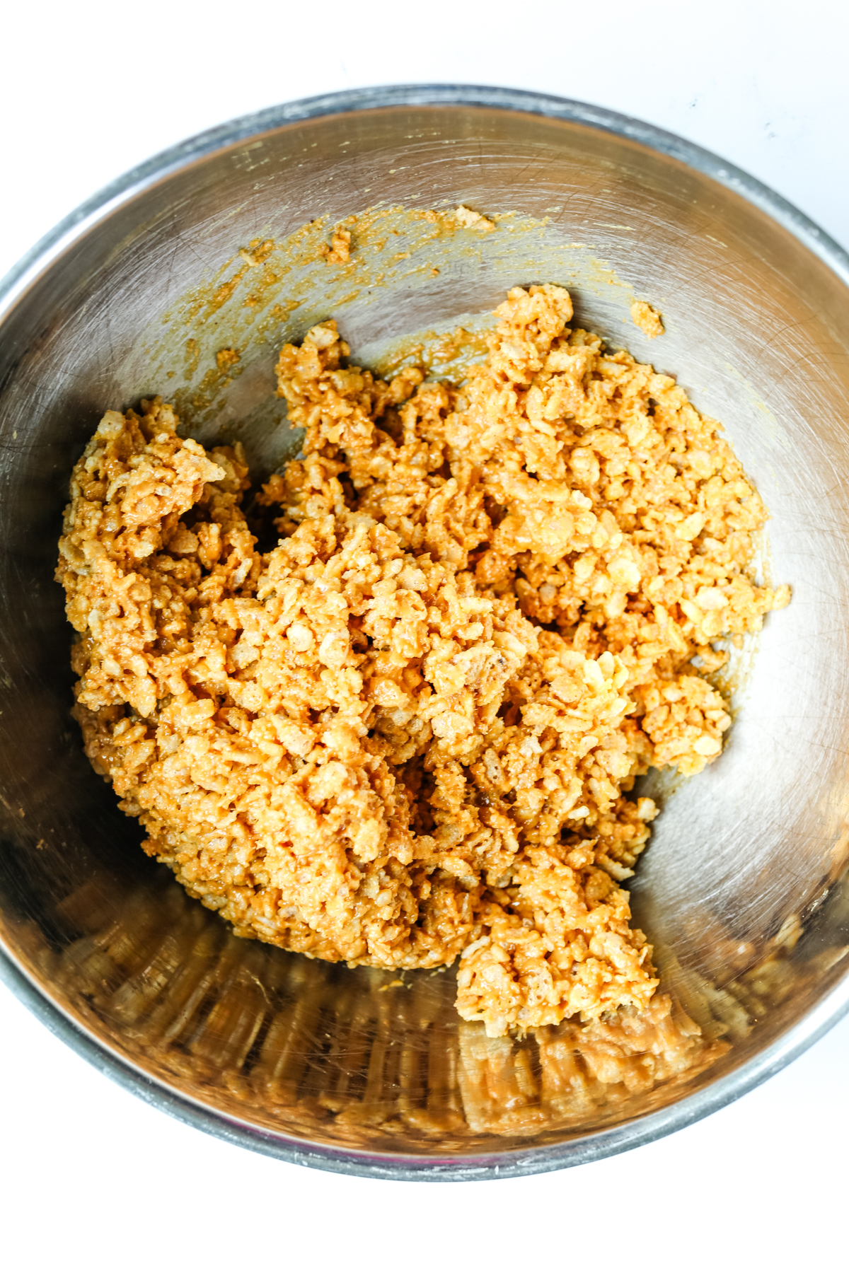 a stainless steel bowl with rice Krispy cereal and peanut butter mixed together