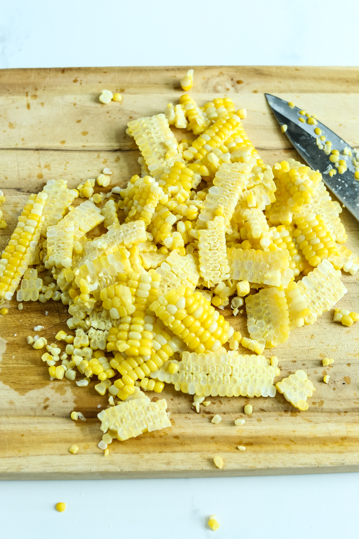 fresh corn on a wooden cutting board with a knife