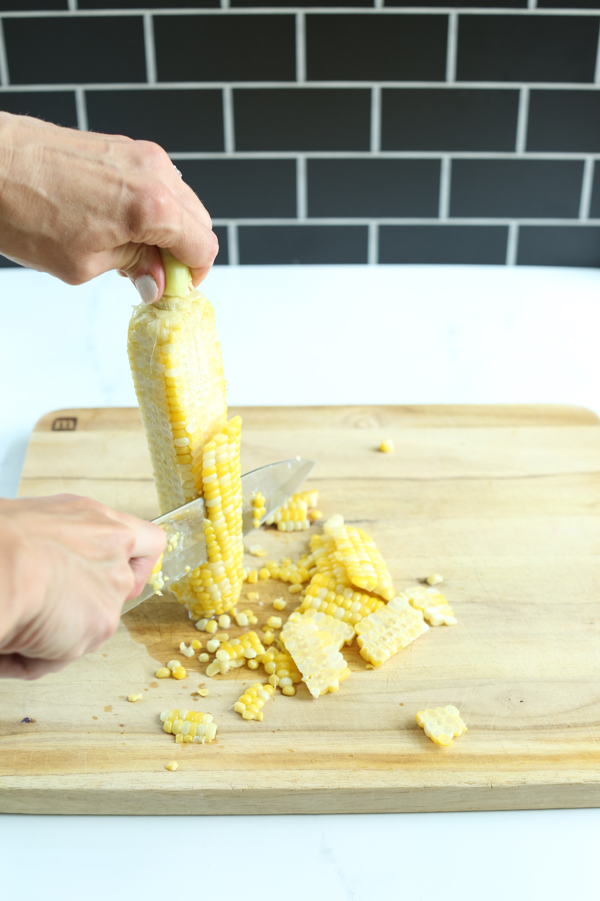 cutting the kernels off of a cob of fresh corn