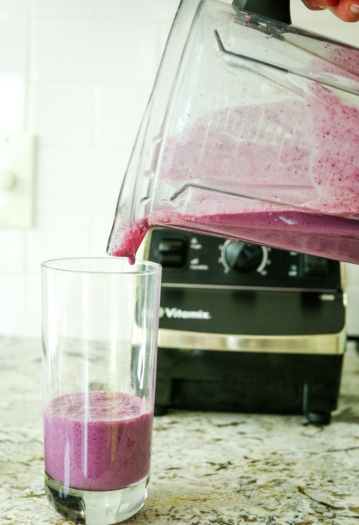 a purple smoothie being poured from the blender into the glass