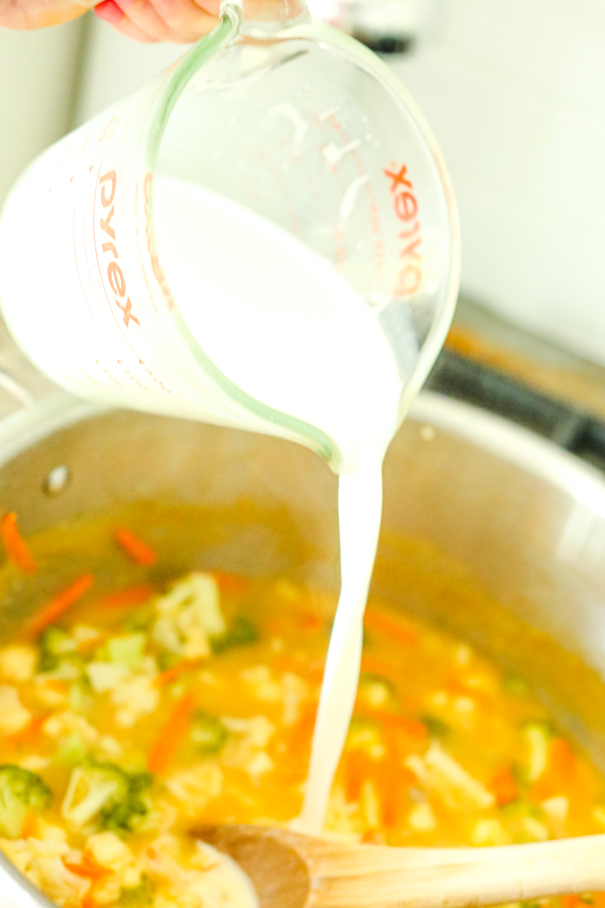 pouring milk into a pot of soup