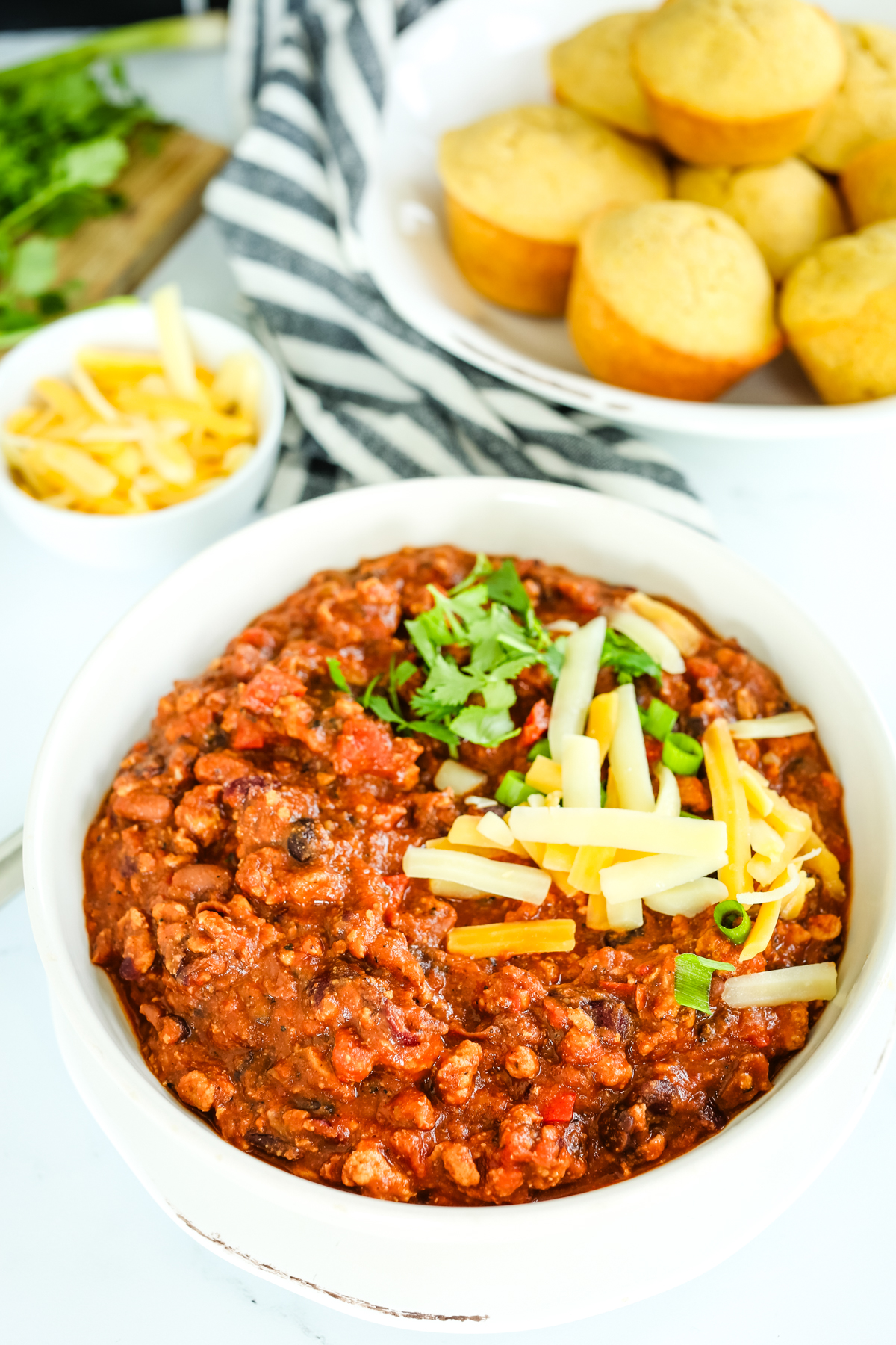 a bowl of chili with cheese and cilantro on top