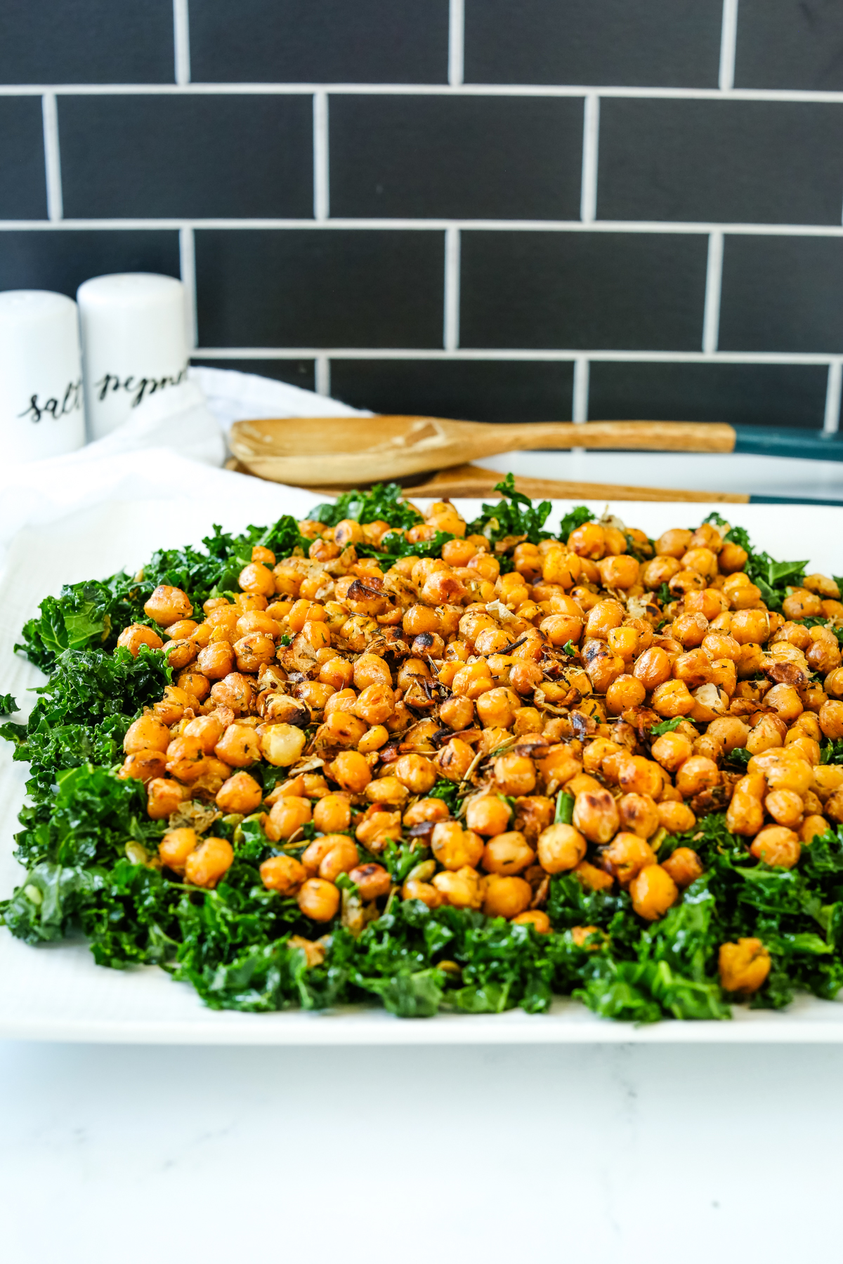 Chickpea and Kale Salad with salad servers in the background