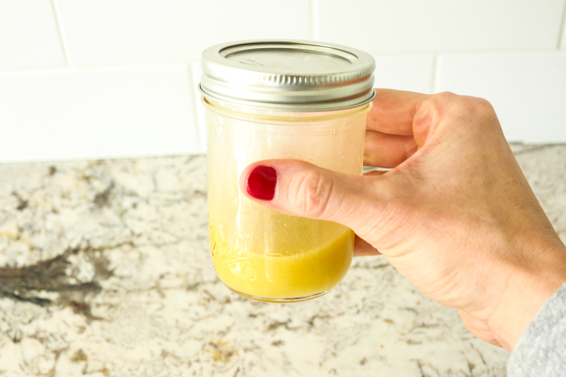 a yellow hued dressing in a mason jar