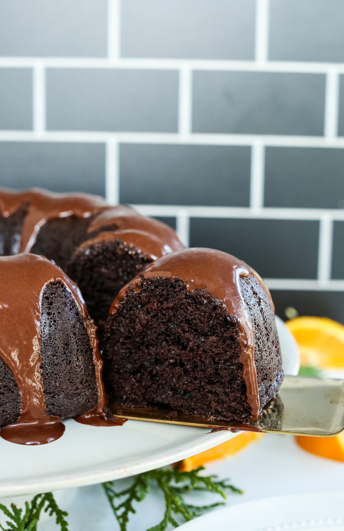 a chocolate bundt style cake with chocolate glaze and a piece being removed