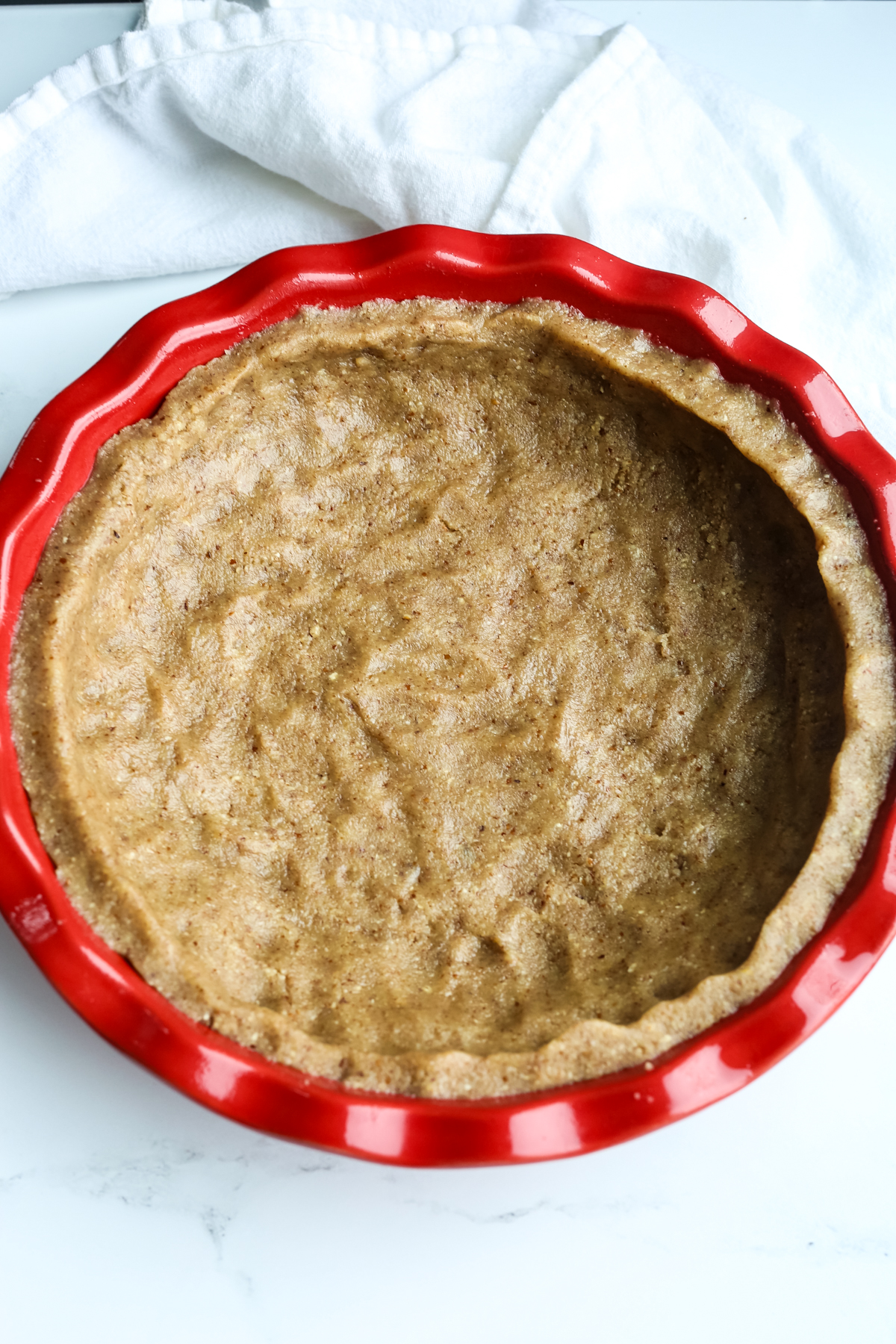 a unbaked crust in a red pie dish