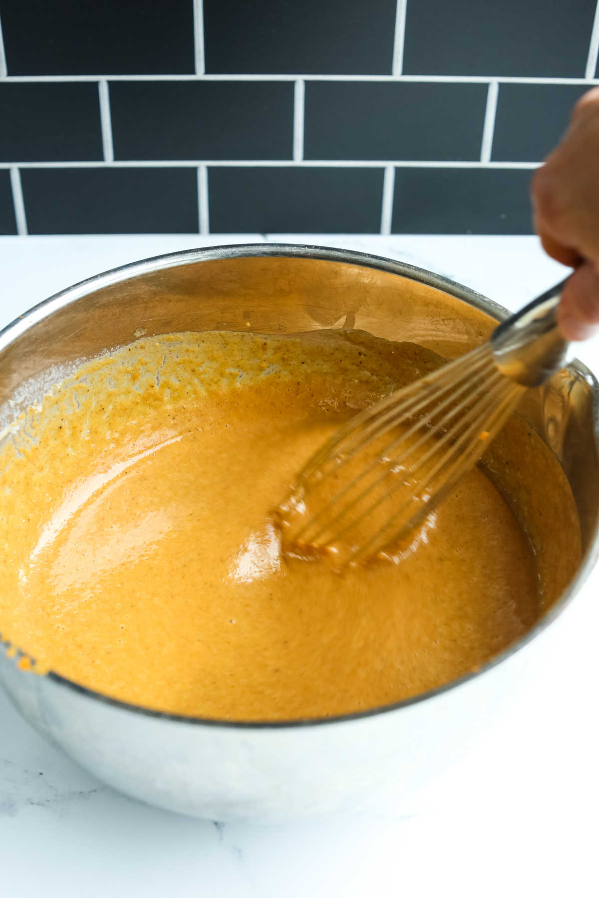 whisking the pumpkin pie filling in a stainless steel bowl