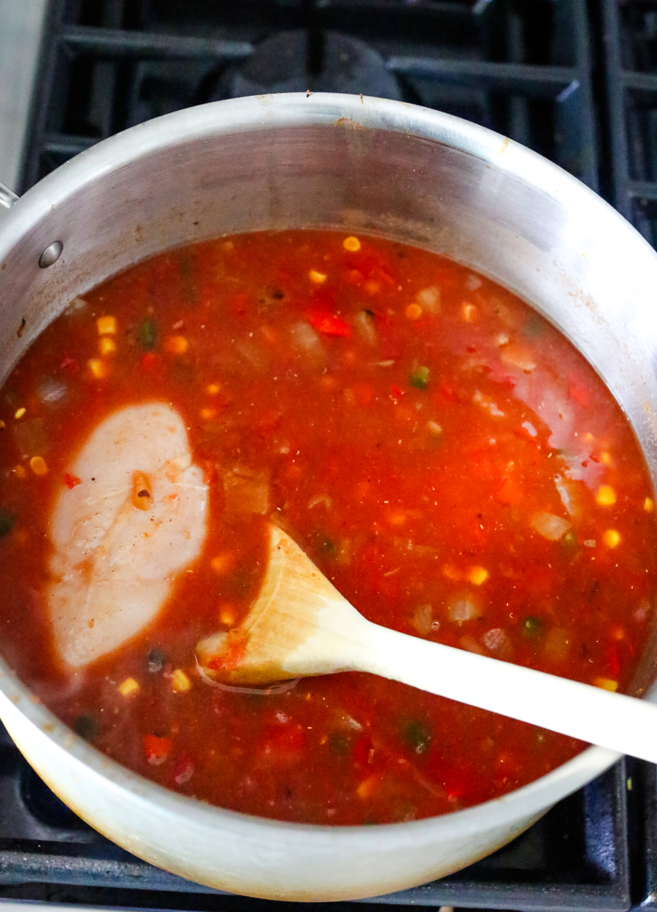 a raw chicken breast in a pot of soup
