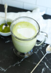 a green beverage with white frothy milk on top
