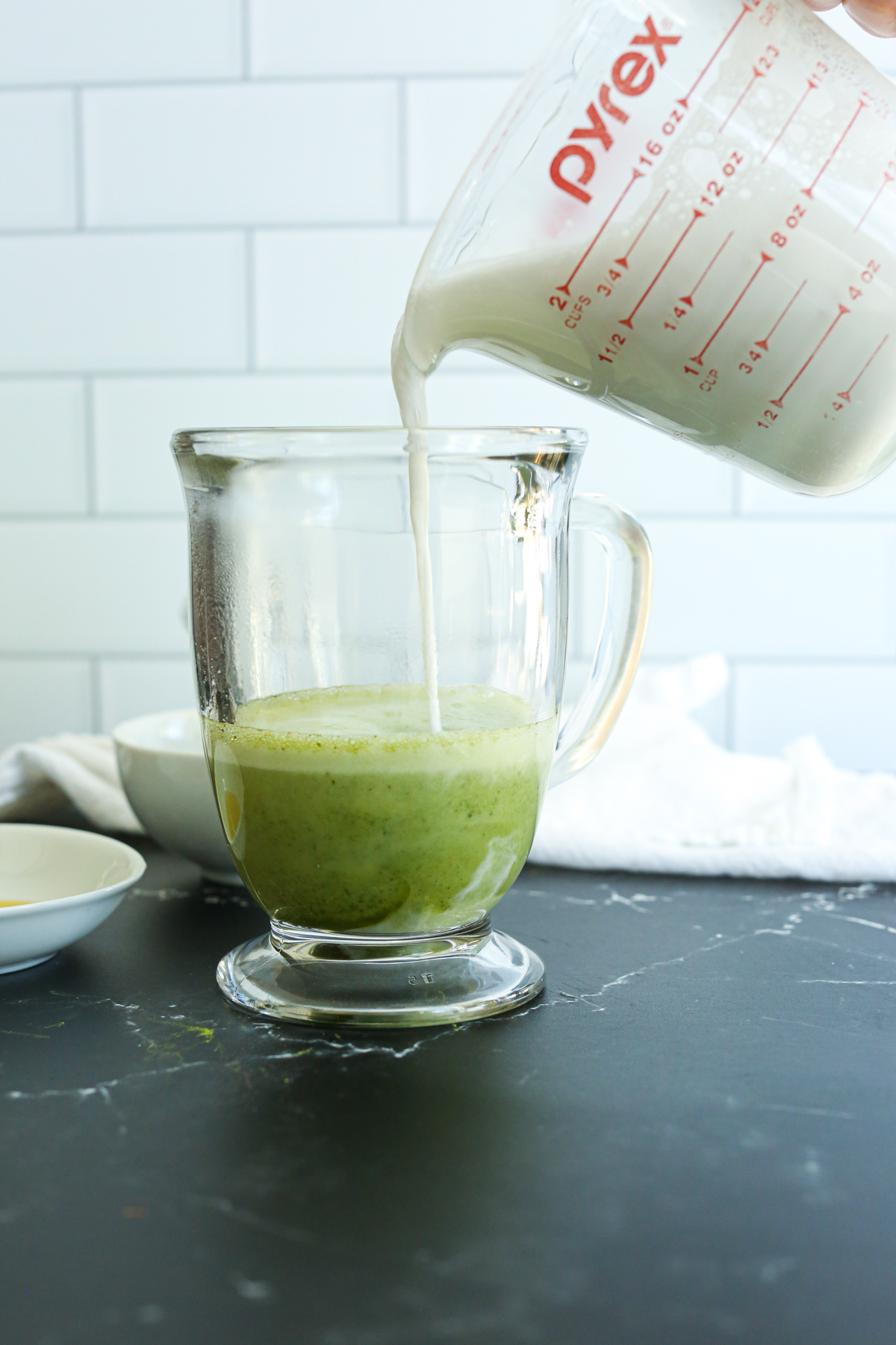 pouring milk into the green tea beverage 