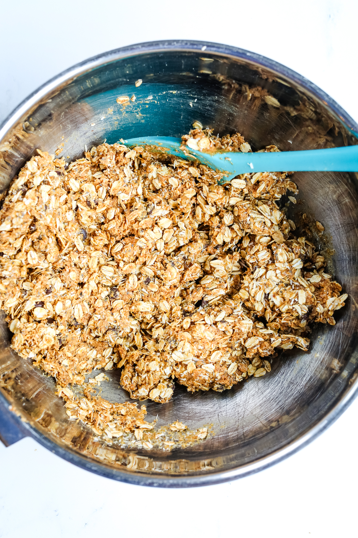 ingredients combined in a silver bowl with a blue silicone spoon