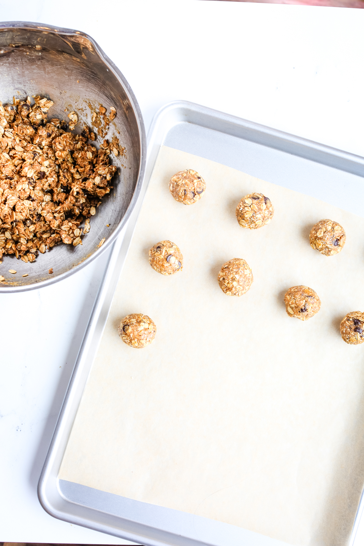 energy balls being rolled and placed on a tray lined with parchment paper 