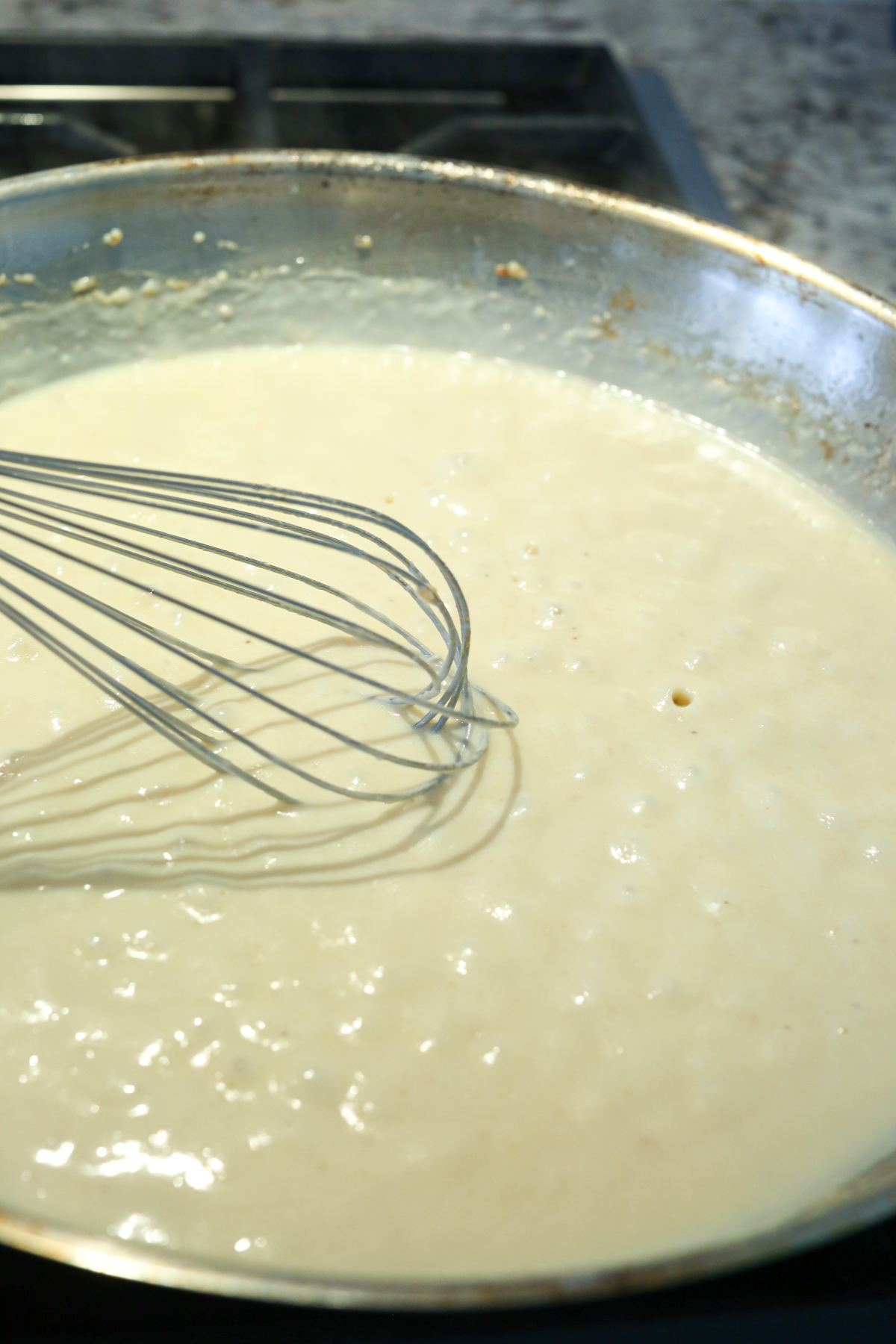 whisking a cheese sauce in a skillet