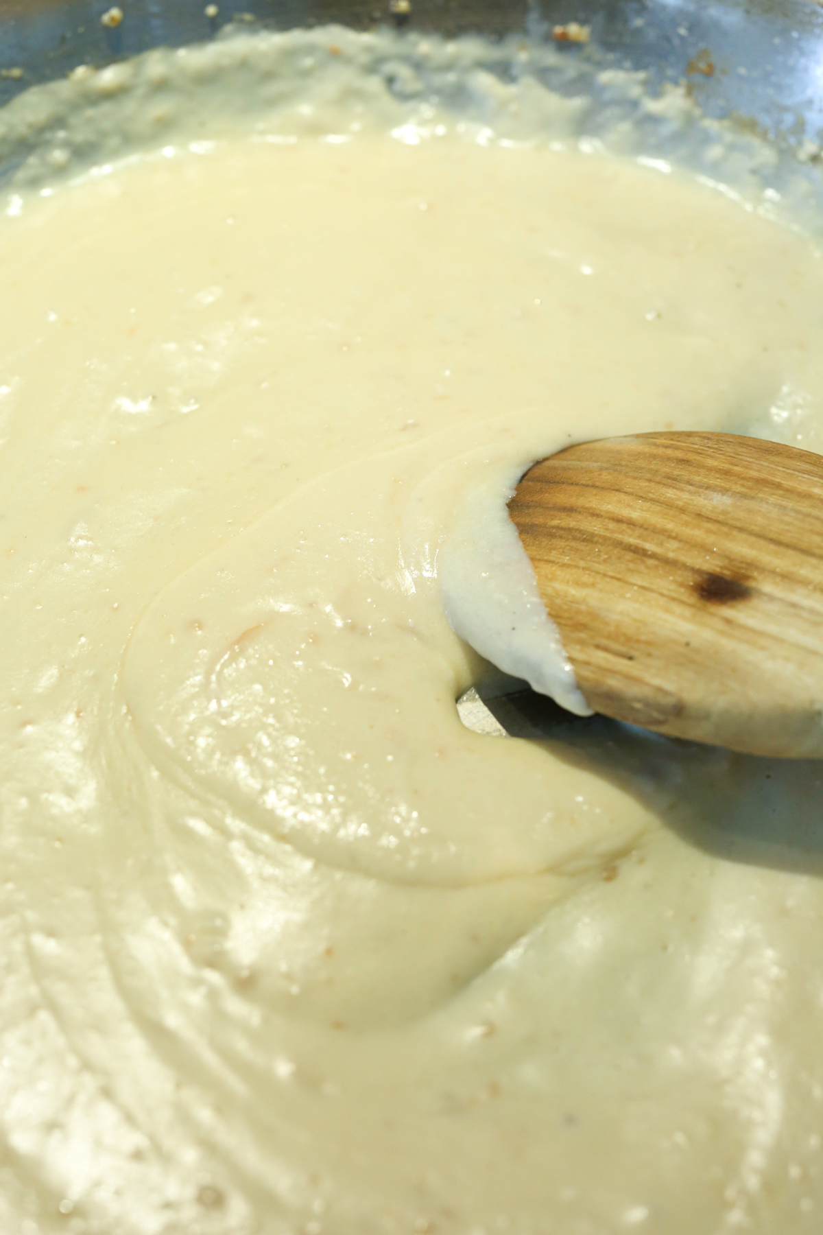 cheese sauce with a wooden spoon in a skillet