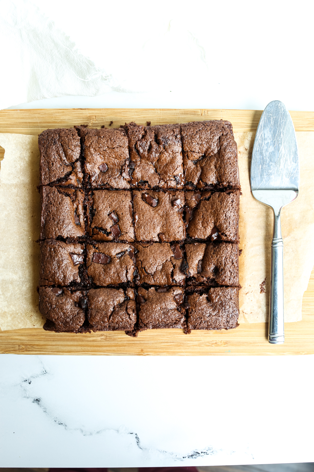 chocolate tahini brownies on a cutting board after being cut into 16 squares