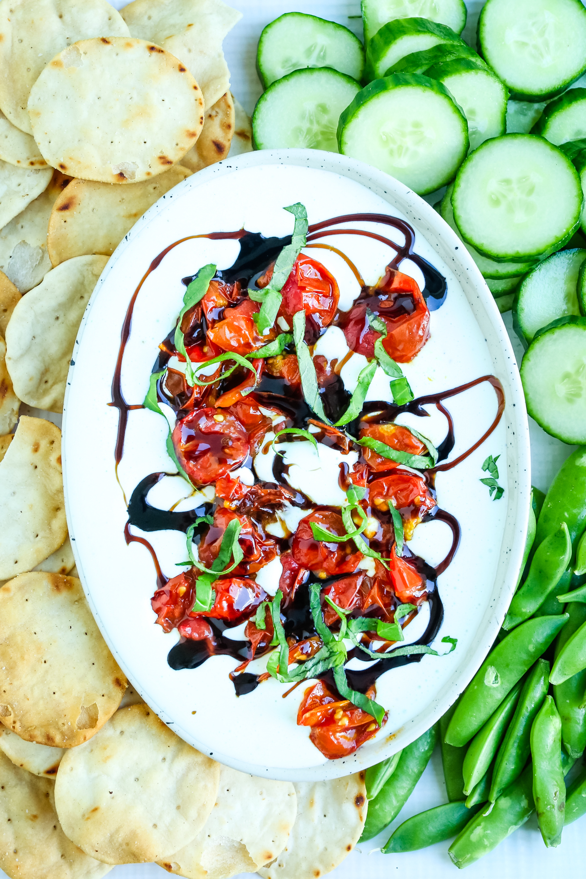 a bowl of cottage cheese dip with cucumbers and pita chips surrounding it