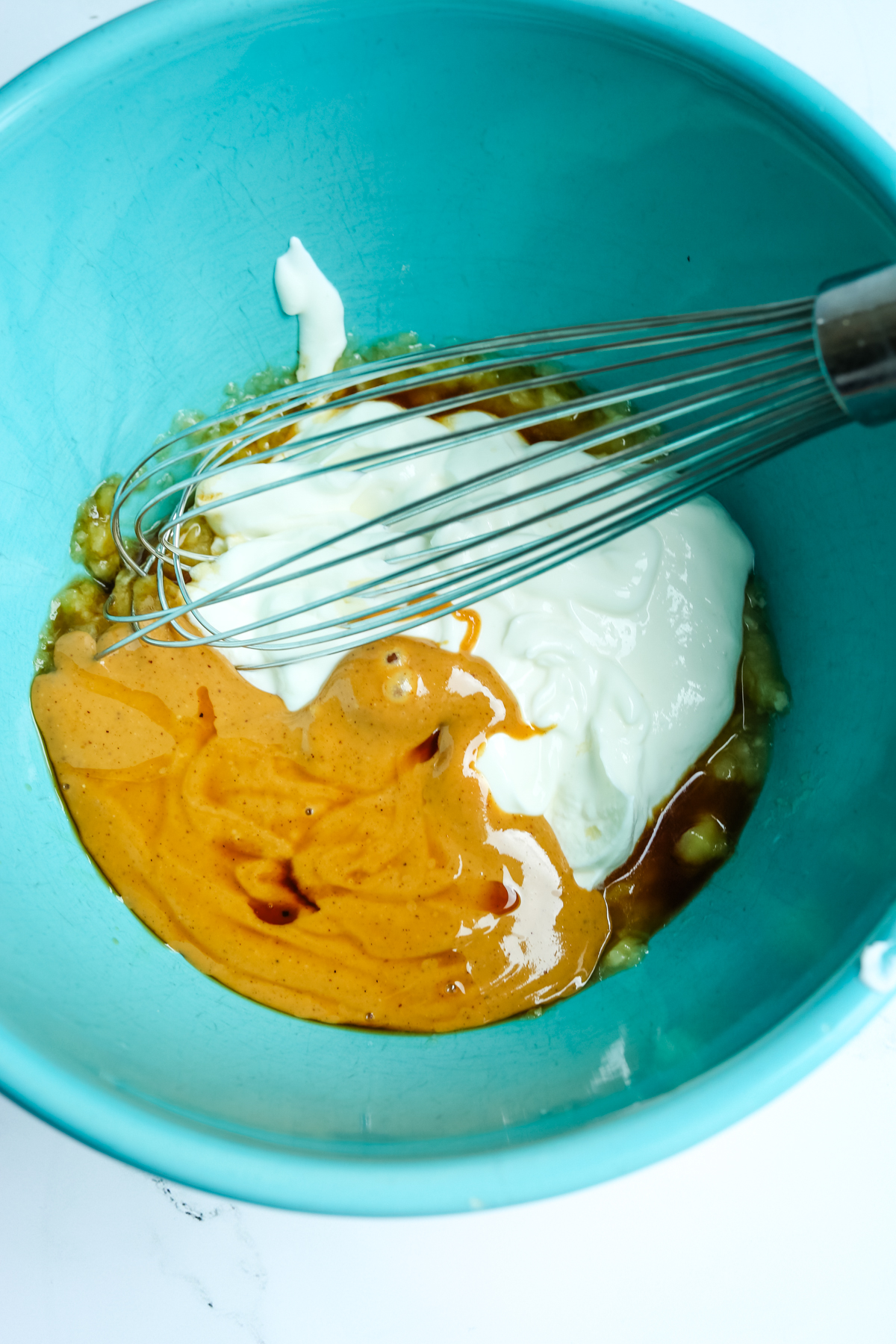 whisking together yogurt and peanut butter in a turquoise blue bowl