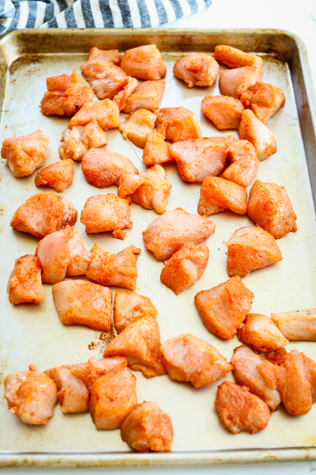 seasoned chicken pieces on a baking tray before baking 