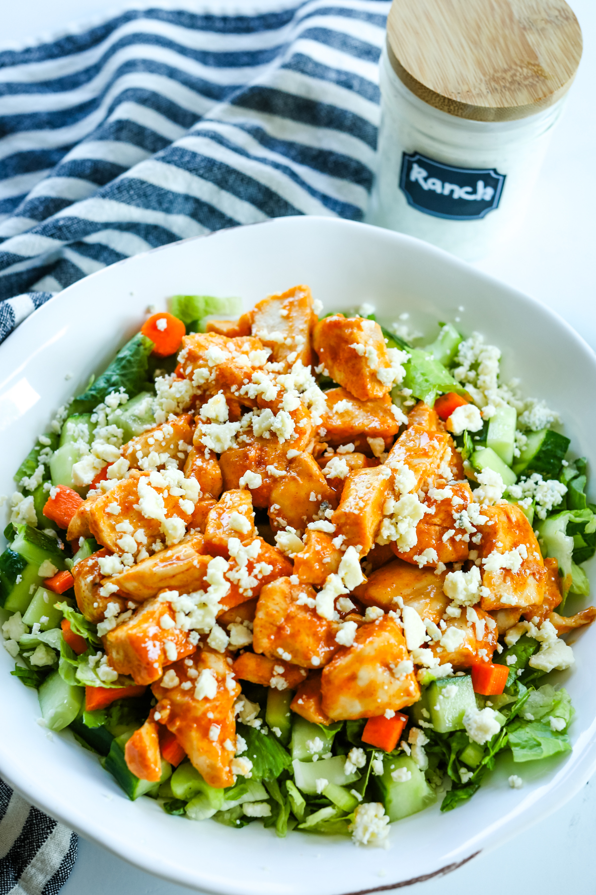 Buffalo Chicken Salad in a white bowl before ranch dressing is poured on top