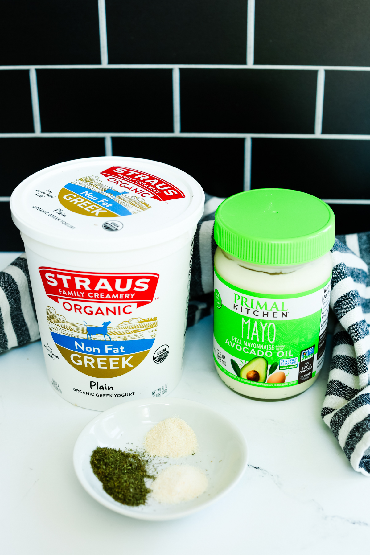 a tub of yogurt, a jar of mayo, and a little plate with seasonings