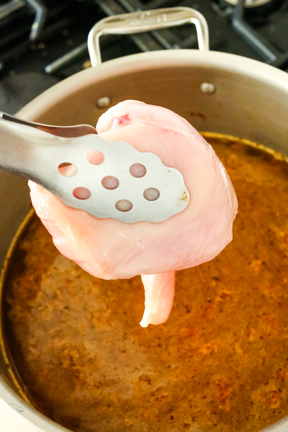 Adding a raw chicken breast to a large pot