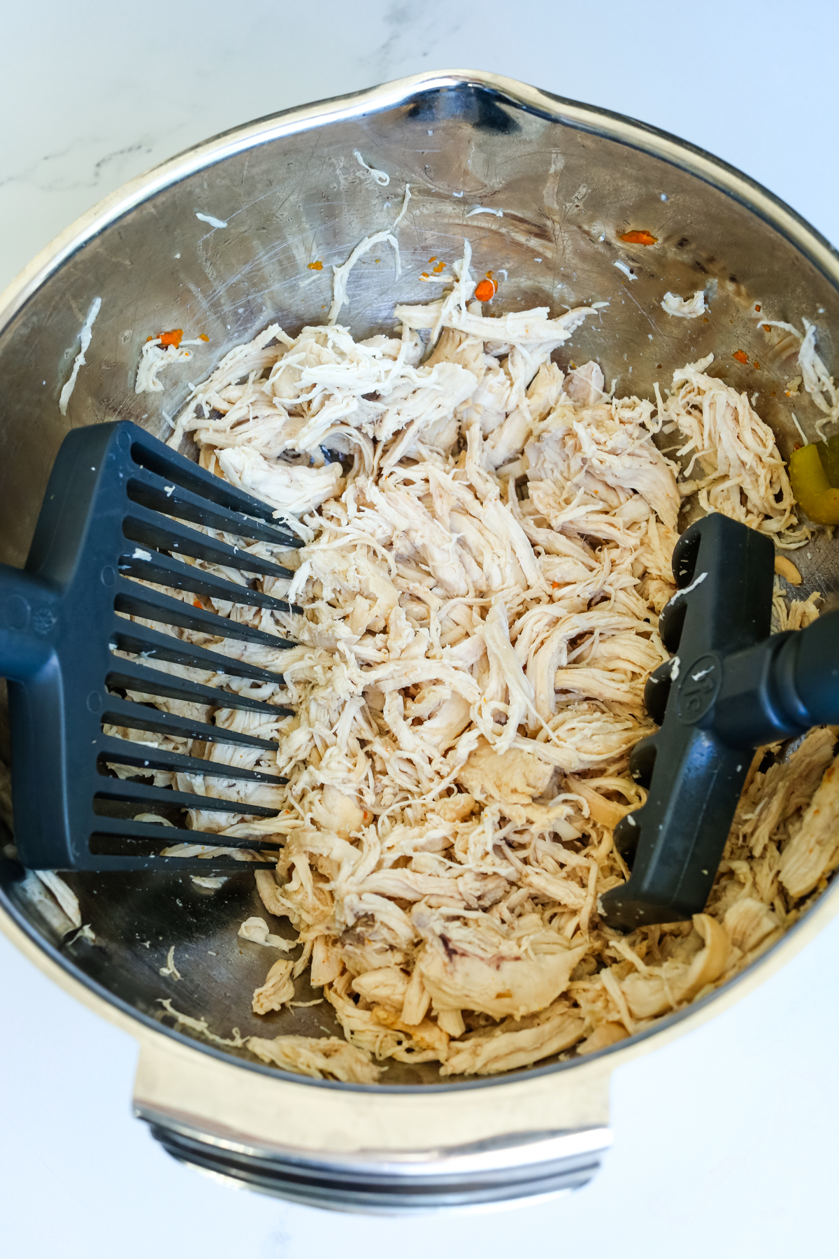 two large black forks shredding chicken 