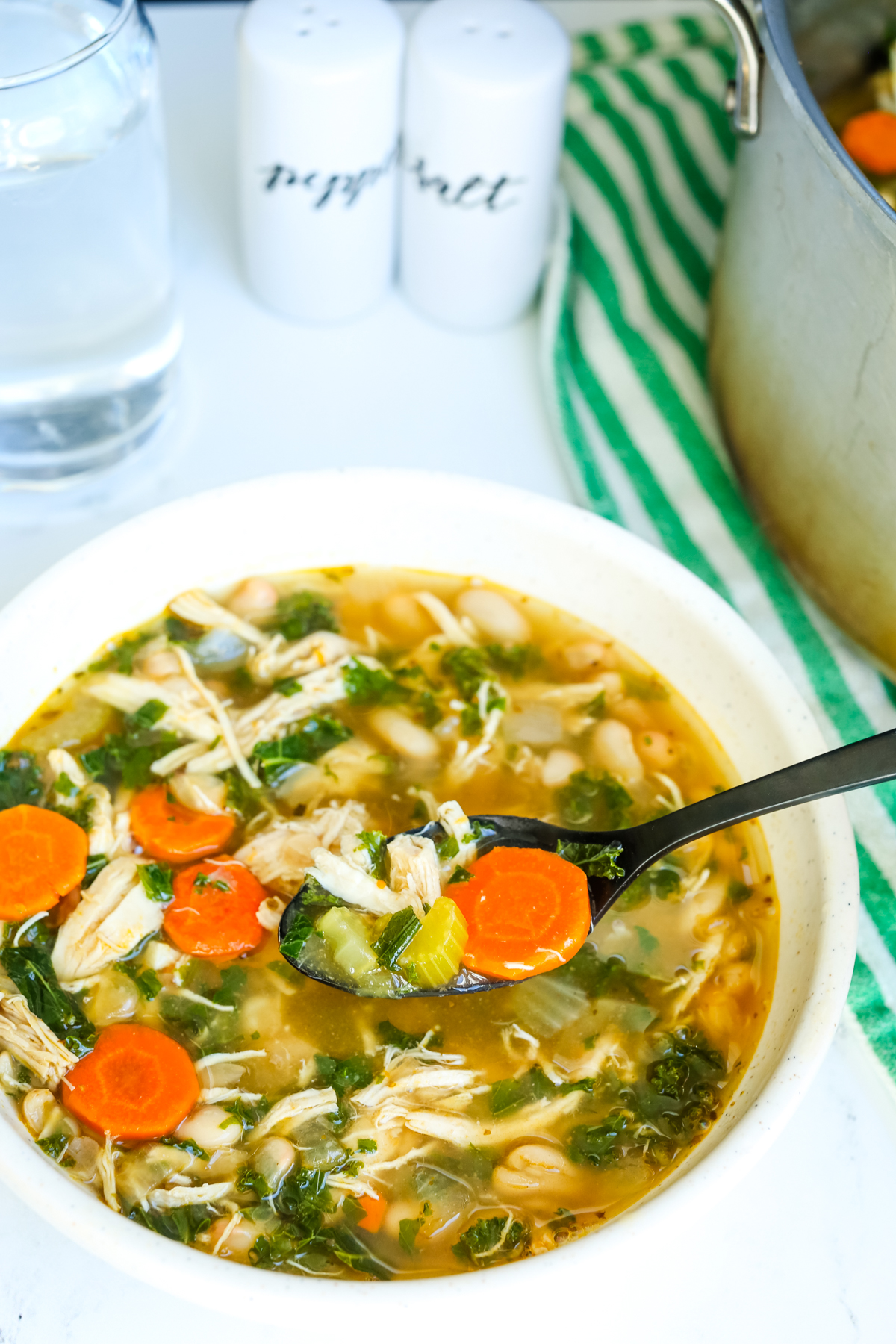 a bowl of chicken white bean soup with a black spoon