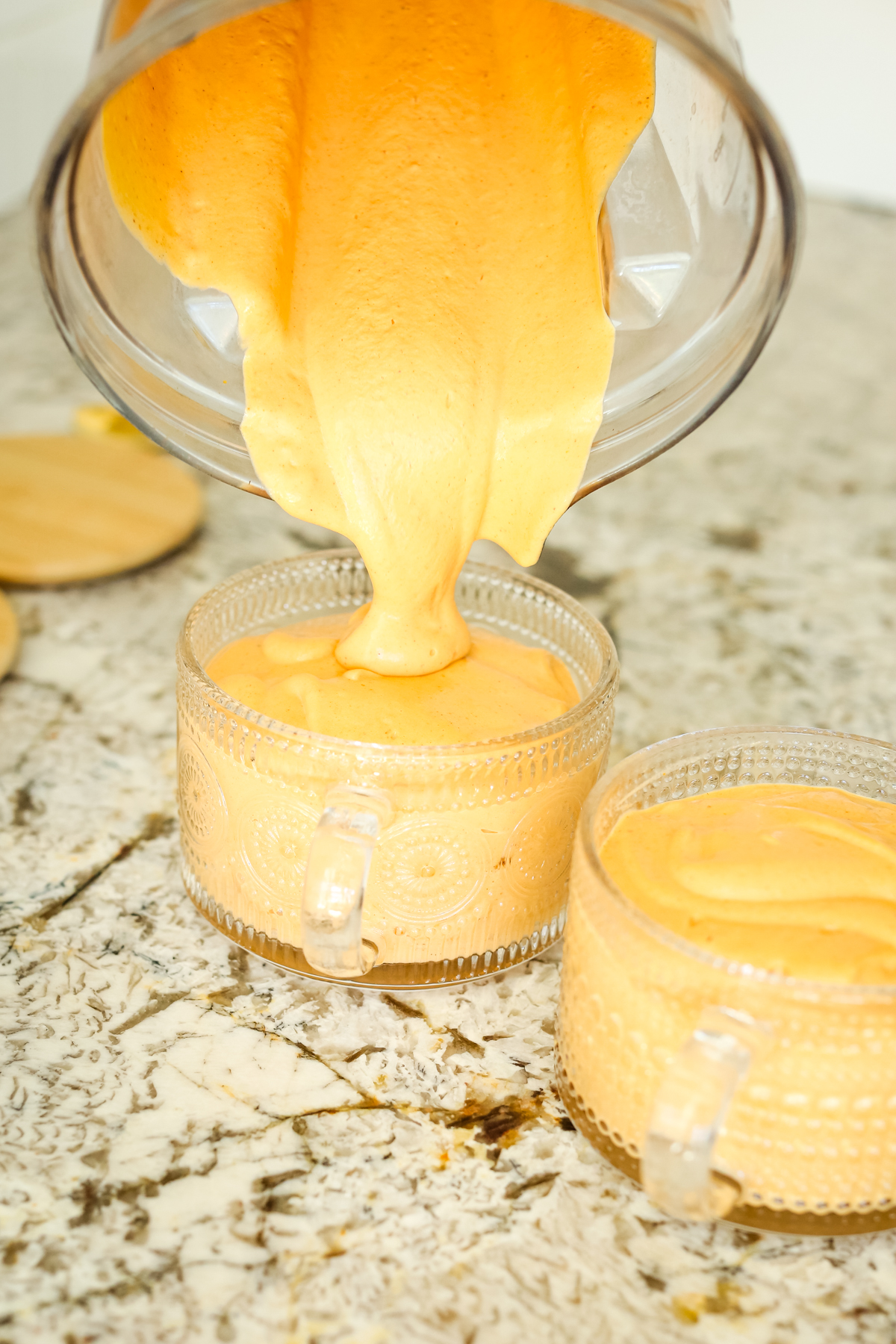 pouring a thick, orange hued liquid into a glass mug