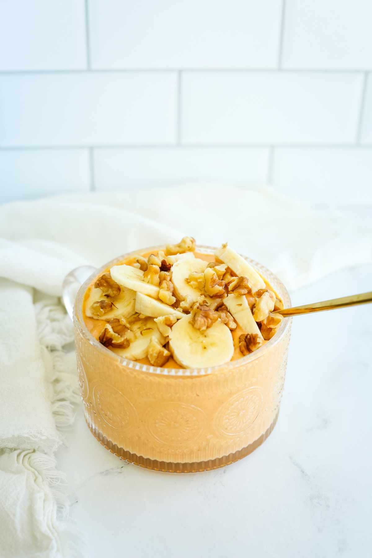 a mug bowl of pumpkin mixture with sliced bananas and walnuts on top