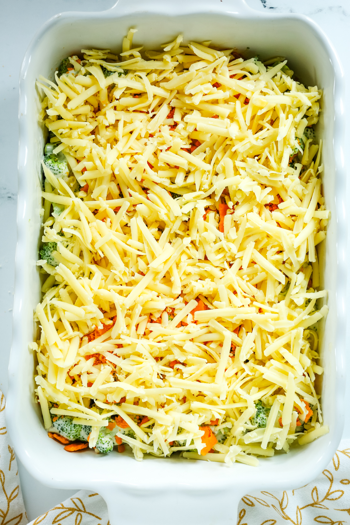 shredded cheese as the top layer of broccoli casserole before baking 