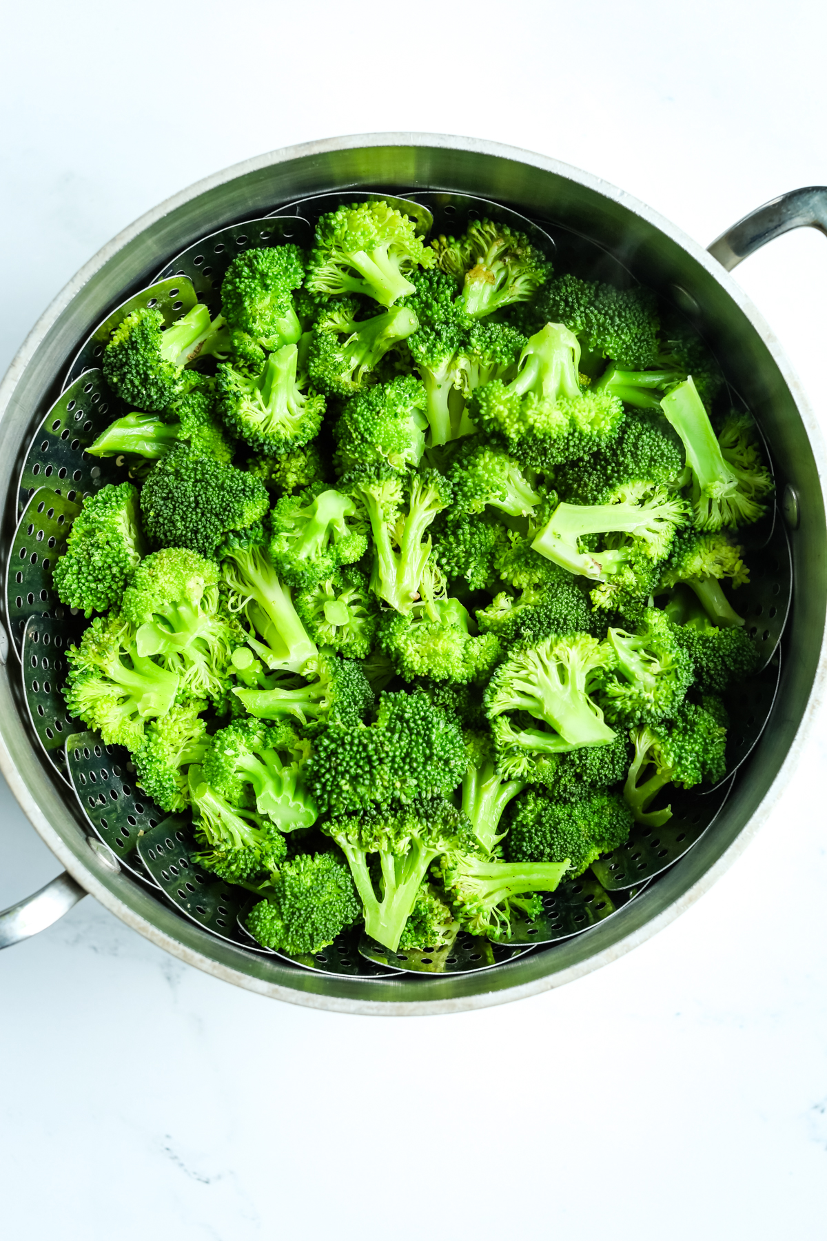 steaming broccoli in a steamer basket in a pot 