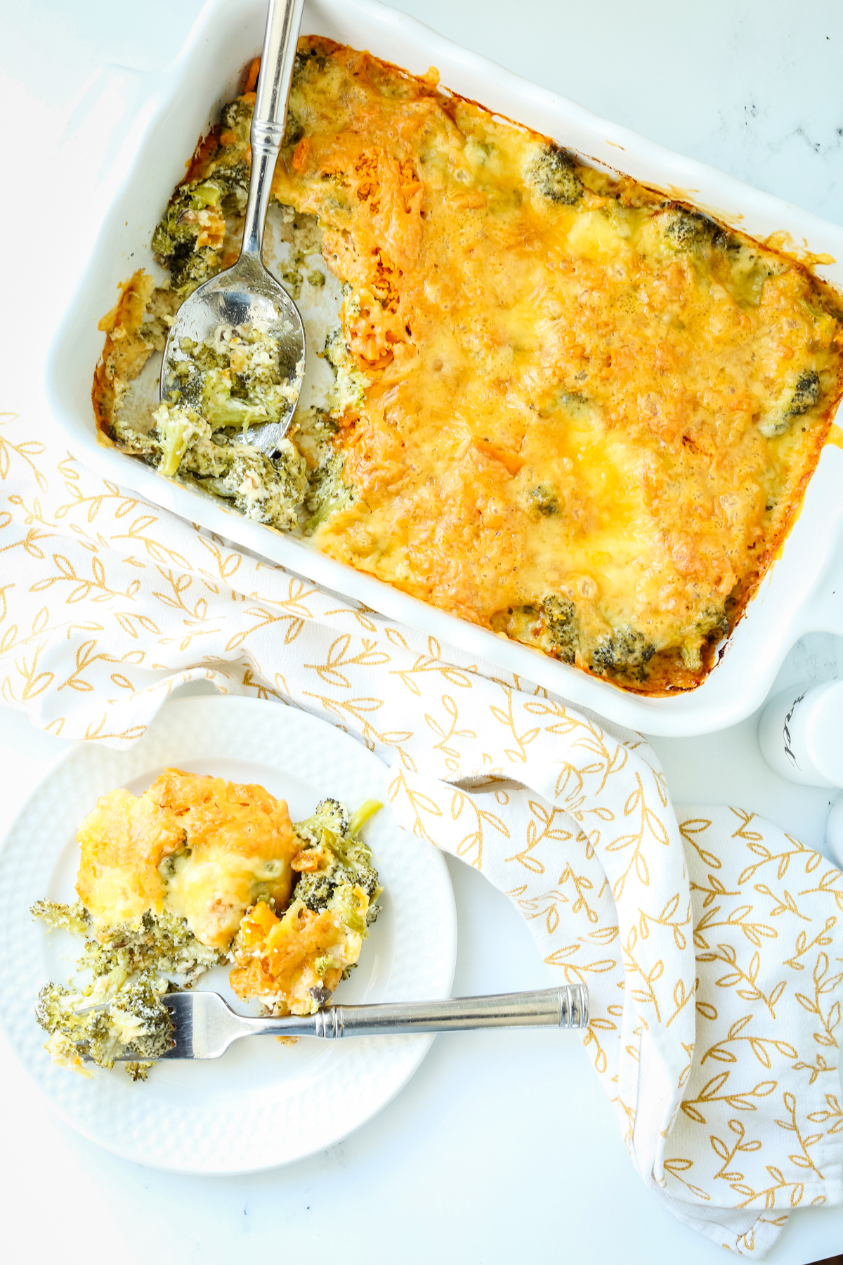 Broccoli casserole in a dish with one serving on a plate