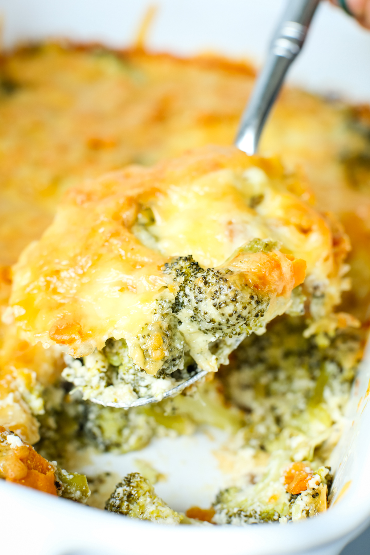 a scoop of broccoli casserole with cheese on top