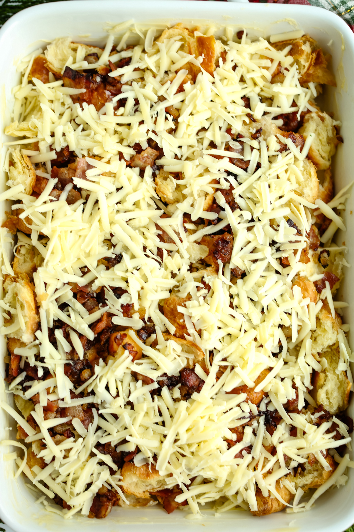 shredded cheese on top of bacon, onions, and croissants 