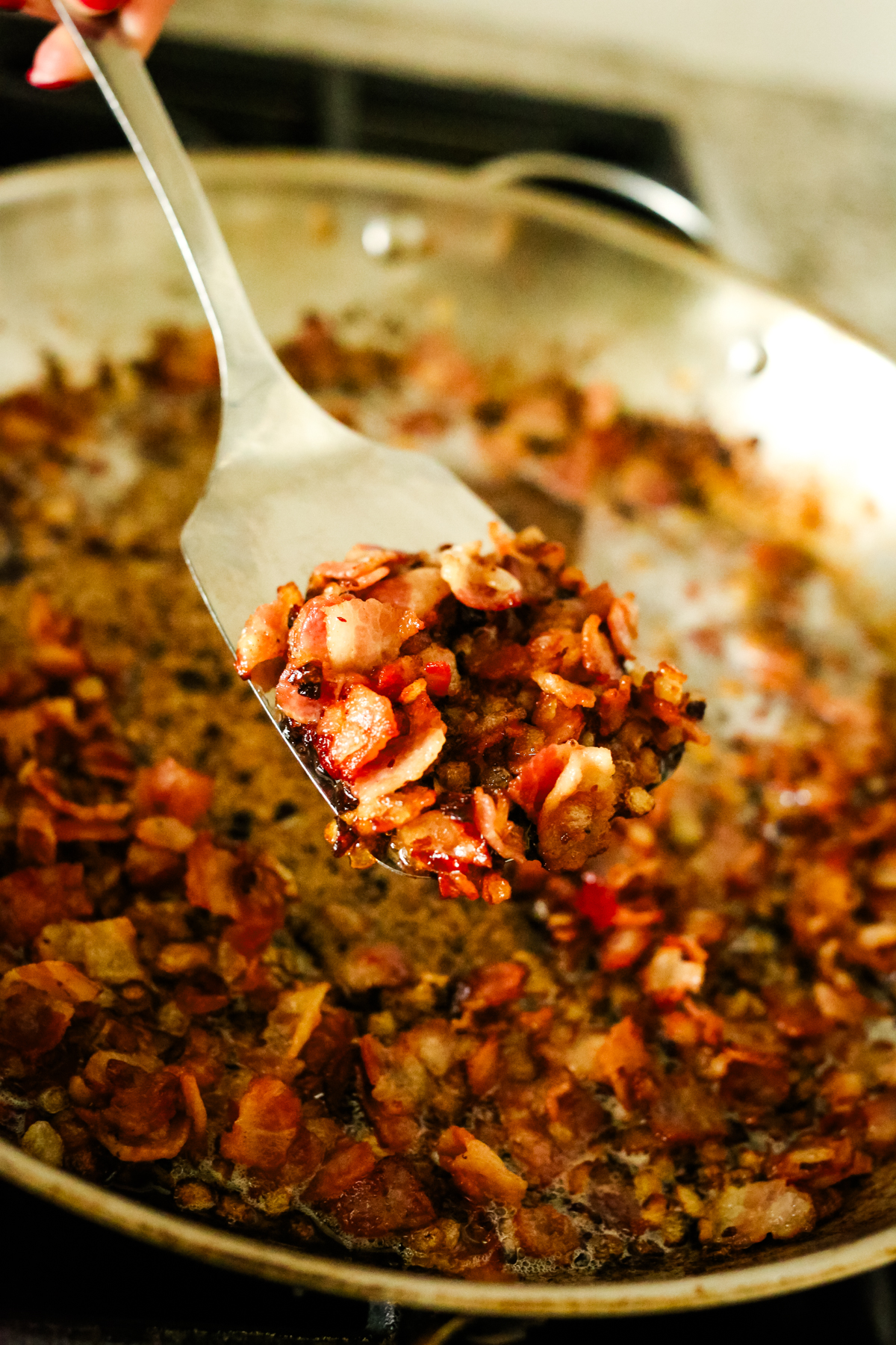 cooked bacon and onions on a slotted metal spatula
