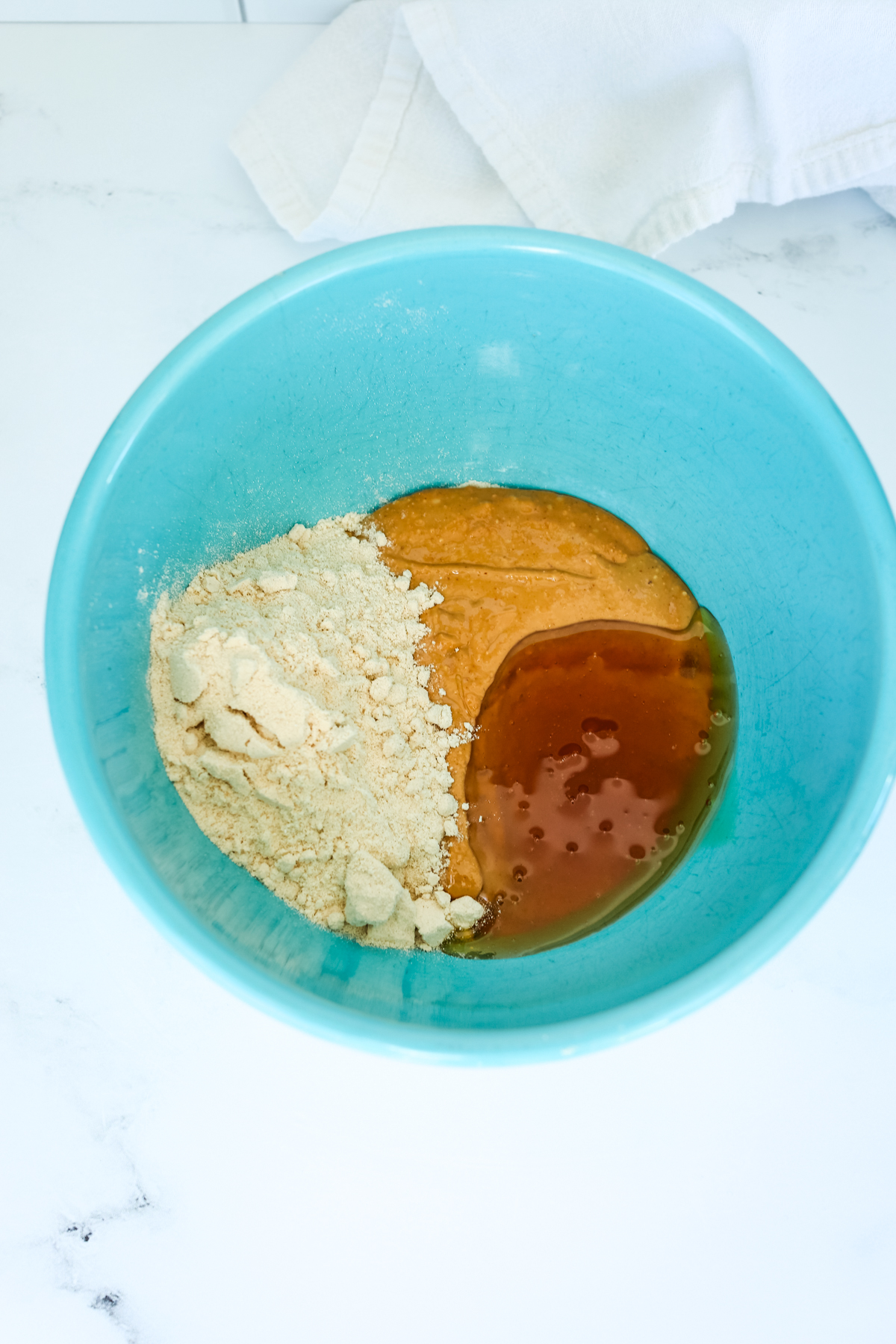 protein powder, honey, and peanut butter in a turquoise blue bowl