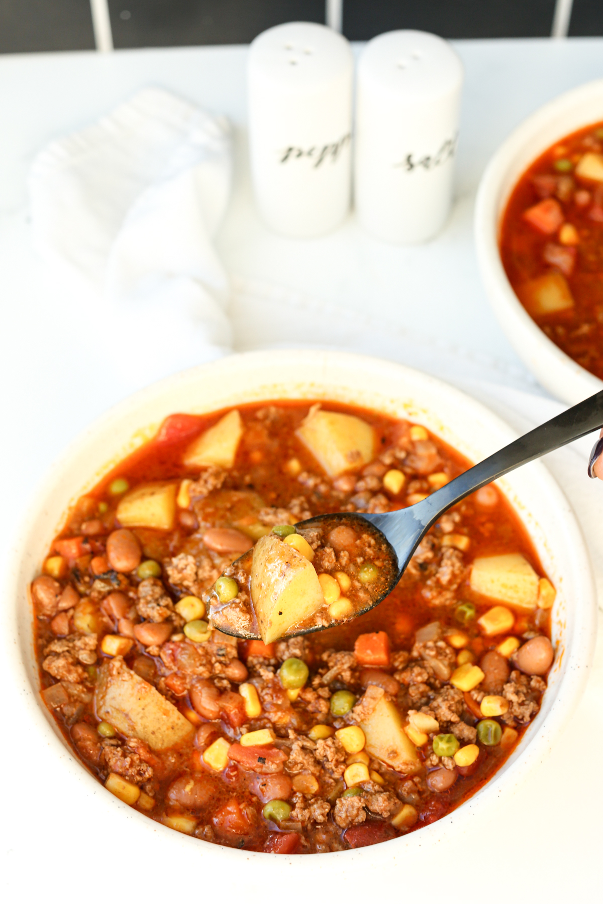 a bowl of cowboy soup with a black spoon taking a spoonful