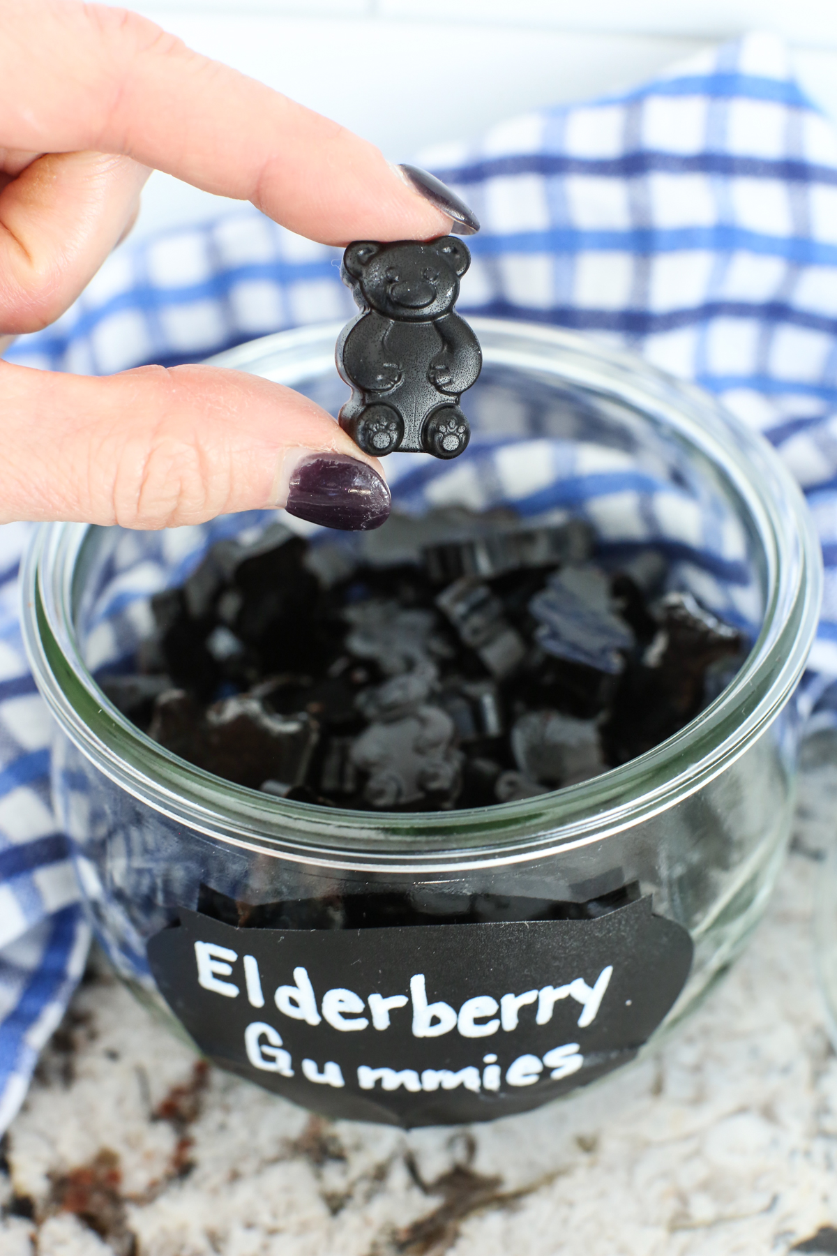 a small deep purple gummy bear in between two fingers