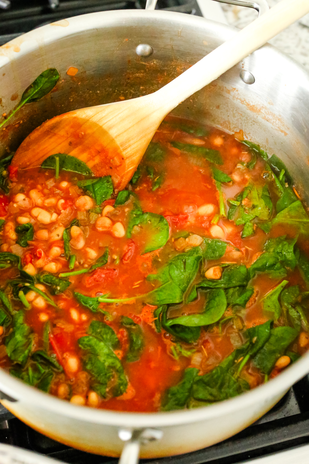 stirring a large pot of soup with a wooden spoon