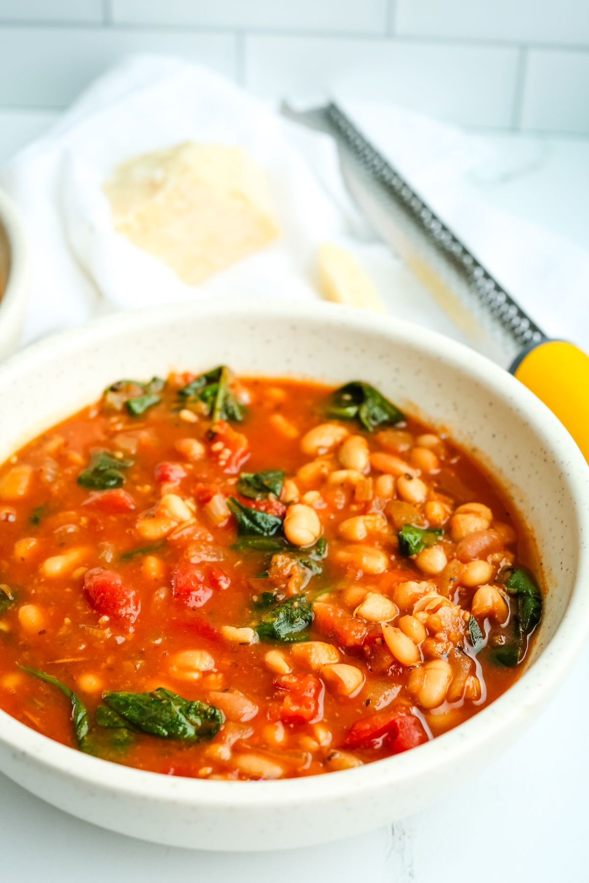 a bowl of soup with beans, spinach, and tomatoes