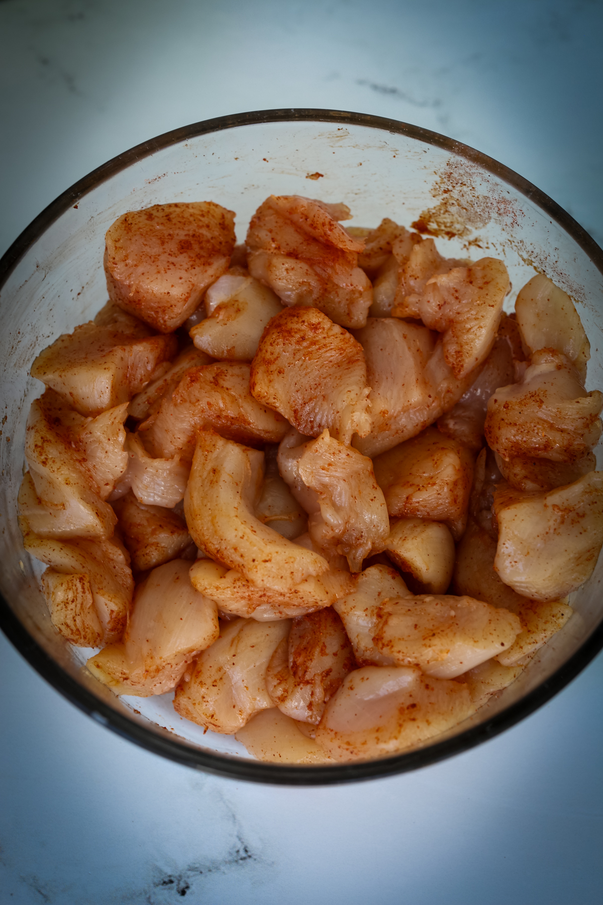raw, seasoned chicken chunks in a glass bowl 