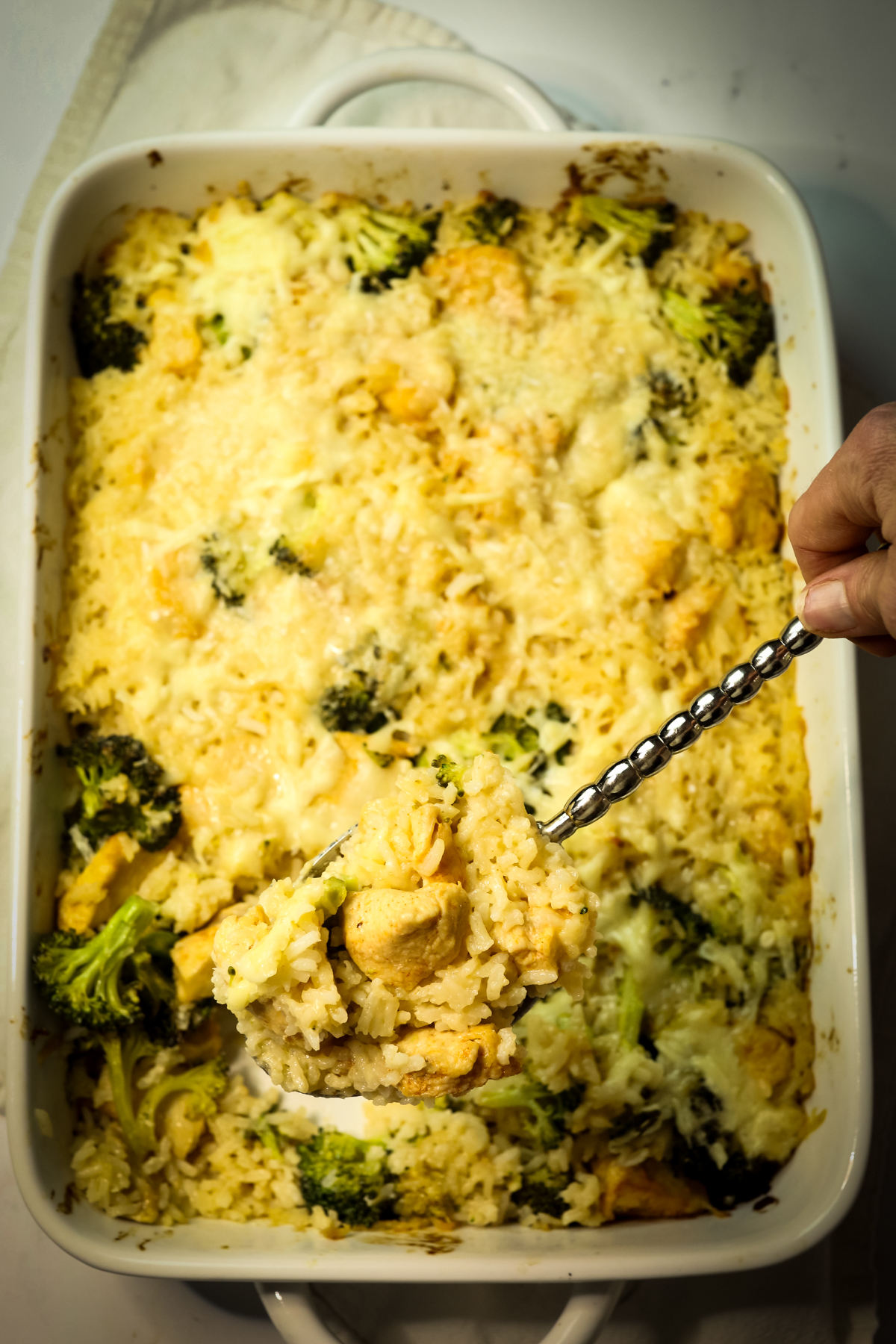 Broccoli Chicken Rice Casserole with a spoon taking a serving from the casserole dish