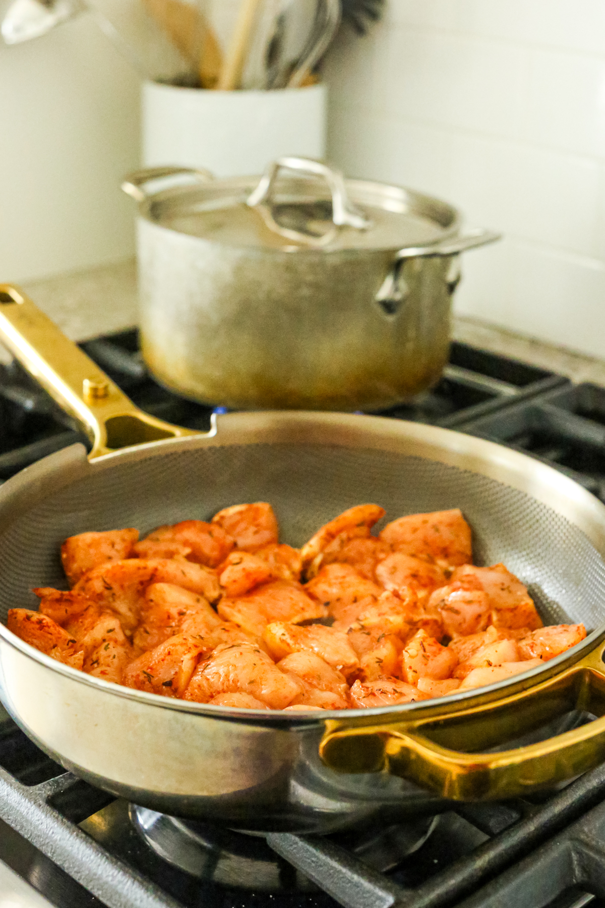 a pot of rice on the back burner with the front burner being used for cooking the chicken chunks