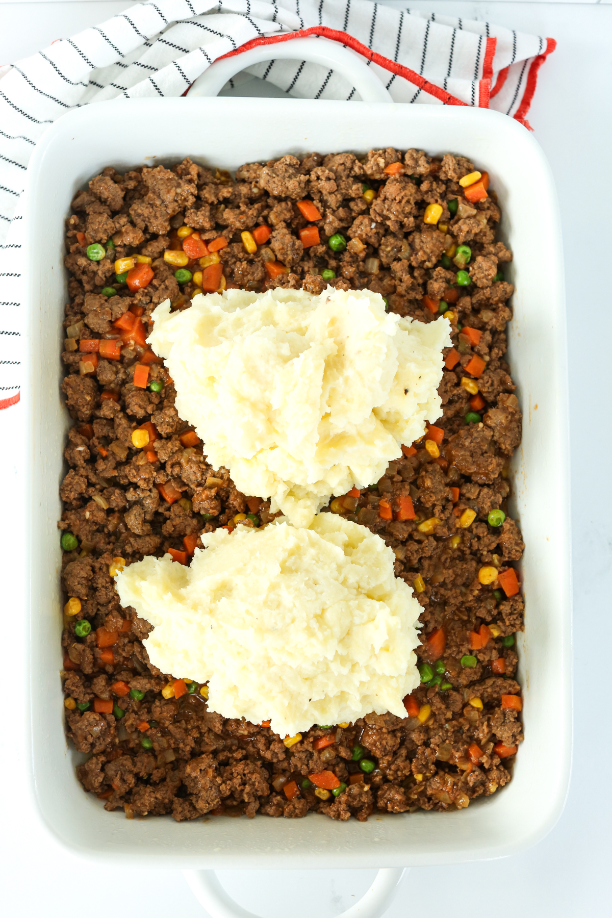 two mounds of mashed potatoes on top of filling in casserole dish