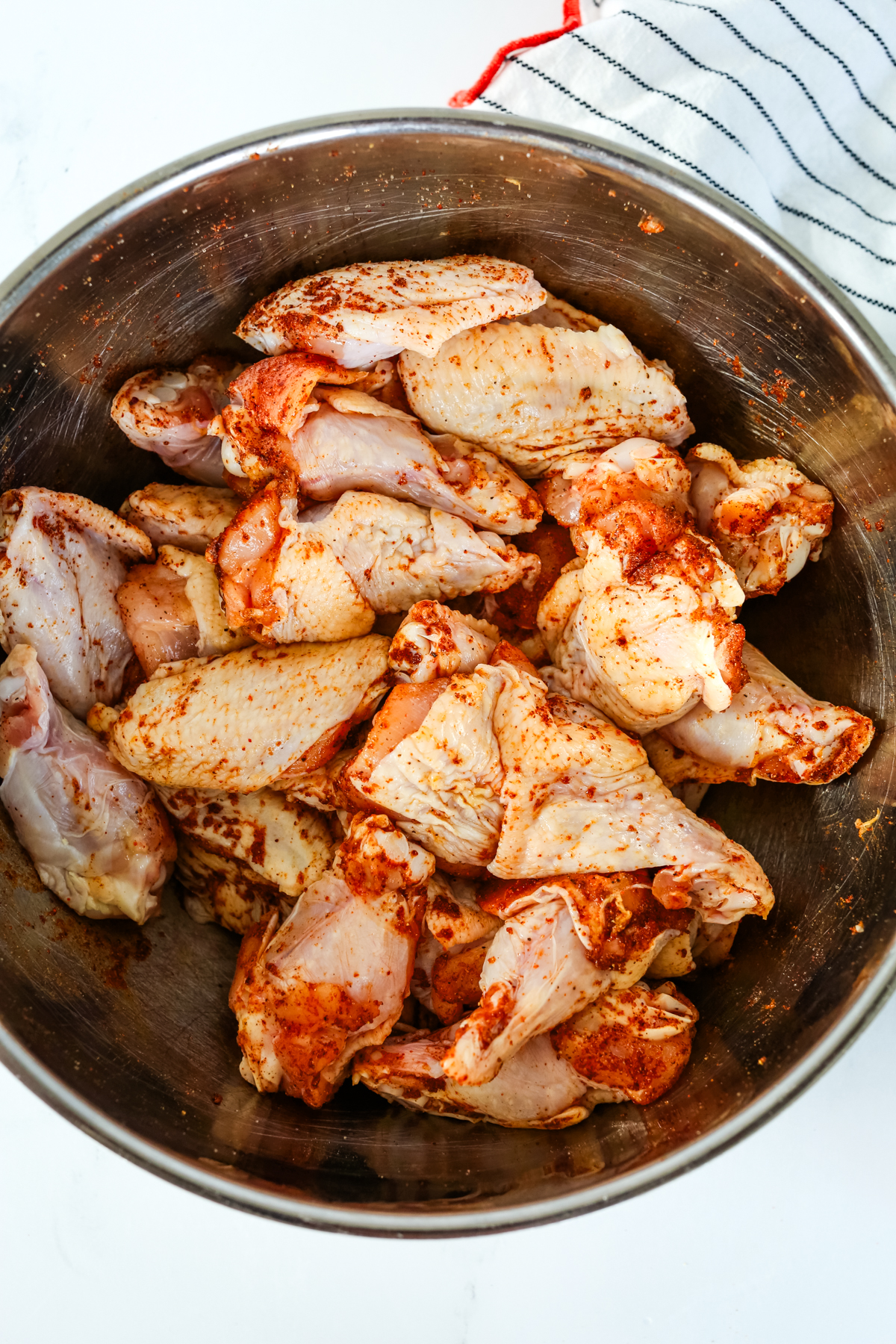 a silver bowl with chicken wings that are coated in a seasoning mix