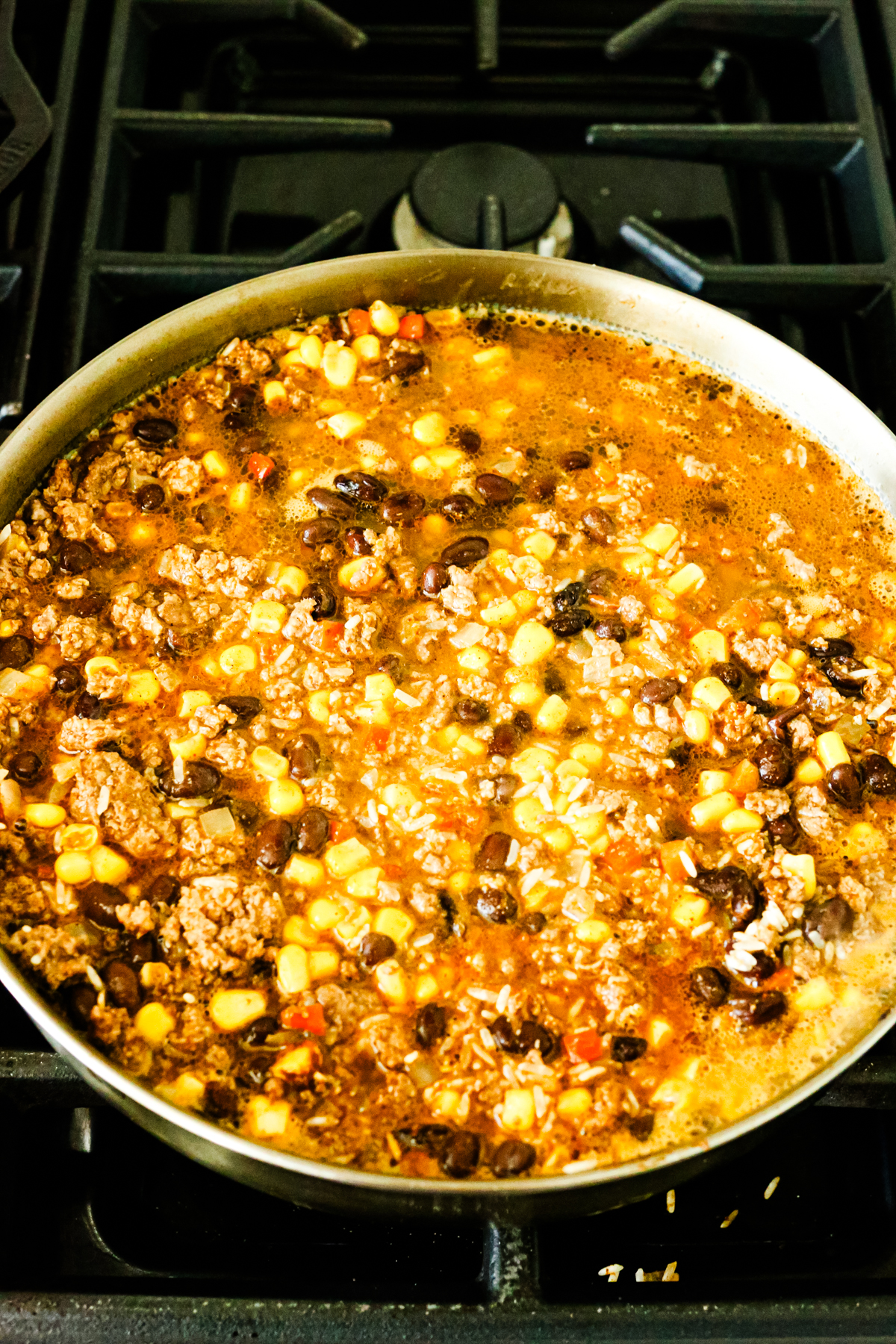 all of the ingredients for Mexican Beef Rice Skillet in the skillet on the stove before cooking