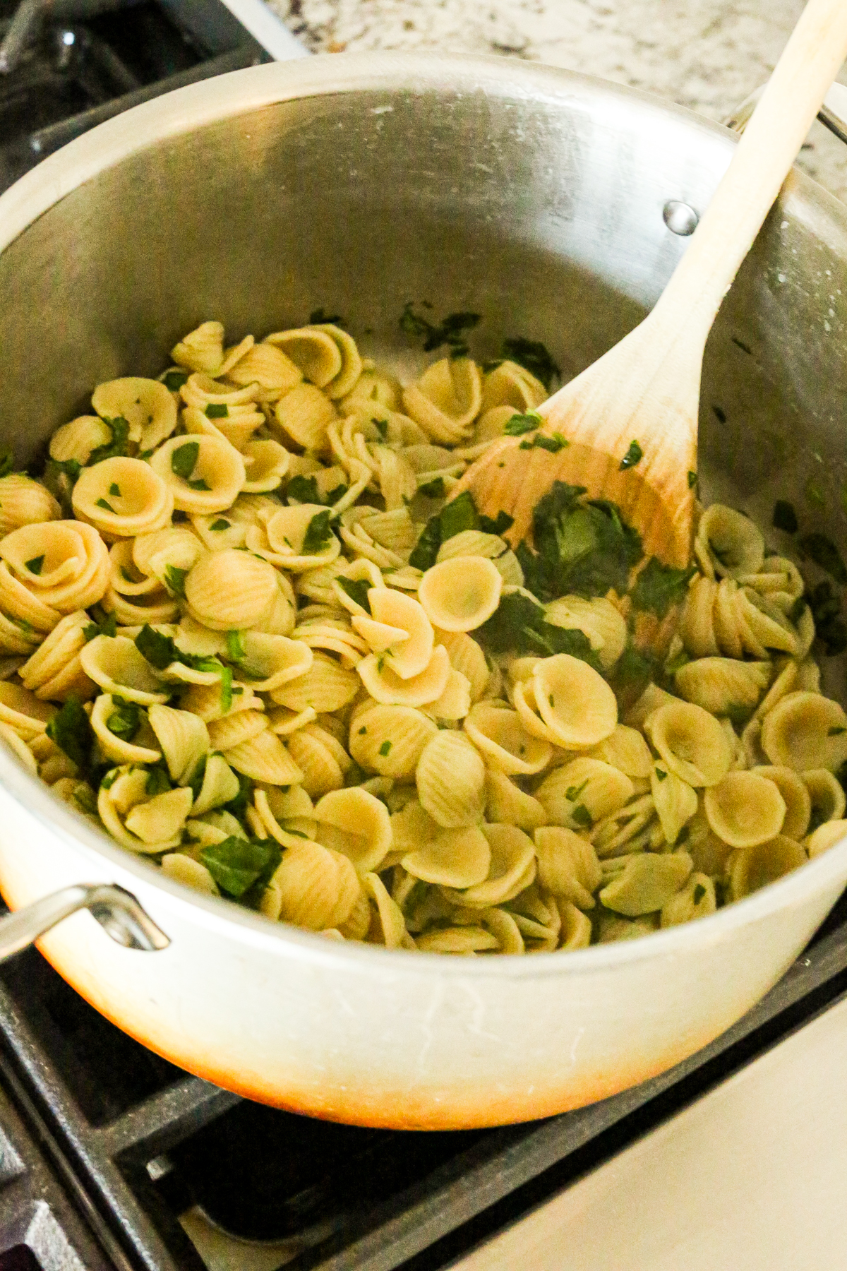 a large pot of pasta stirring spinach in