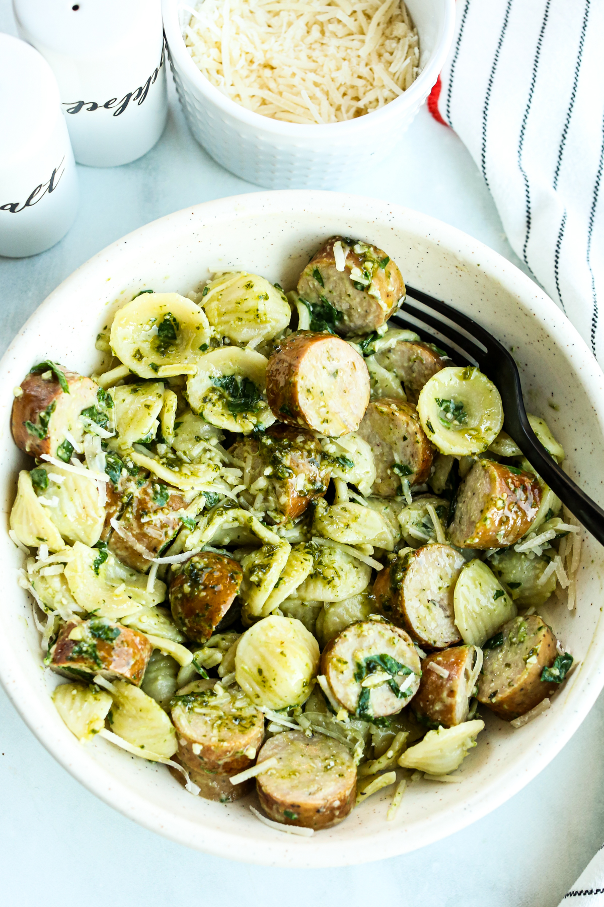 a bowl of Orecchiette pasta with sausage and a black fork in the bowl